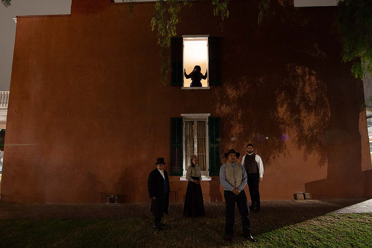 Whaley House hosts outside the house at night, one in the window.